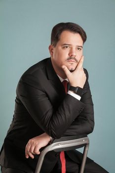 Portrait of business man thinks about something. Indoor, studio shot, isolated on light blue or gray background