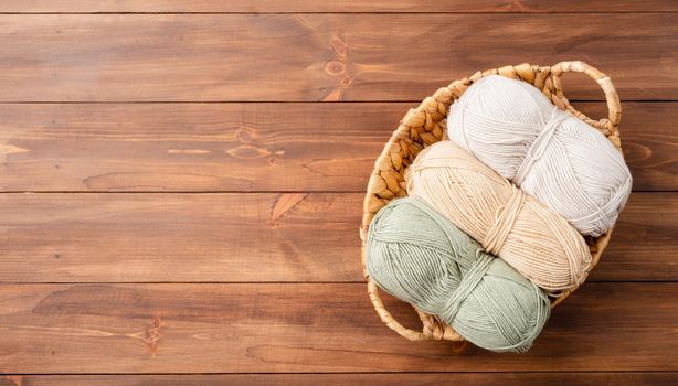 pastel colored yarn wool in a basket on wooden background, top view. Hobbies and leisure. Eco friendly, zero waste