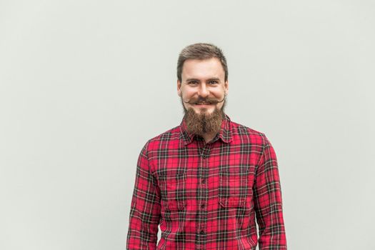 Young adult success businessman looking at camera and toothy smile. Studio shot, gray background