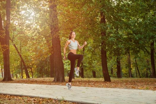 A young beautiful girl is running into the park on cool season at park. .