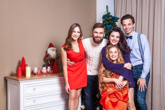 Picture showing happiness family, celebrating christmas at home, looking at camera and posing for family picture. Indoor, studio shot