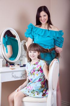 Mother hairdressing her preteen beautiful daughter at home.