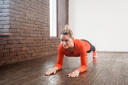 Closeup woman doing plank pose at loft interior room. Studio shot