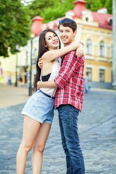 Happy beautiful young couple in love hugging and have a fun together in the city on summer day.