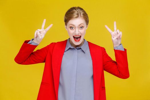 Red head business woman in red suit showing v sign, peace,four sign. Studio shot, isolated on yellow background