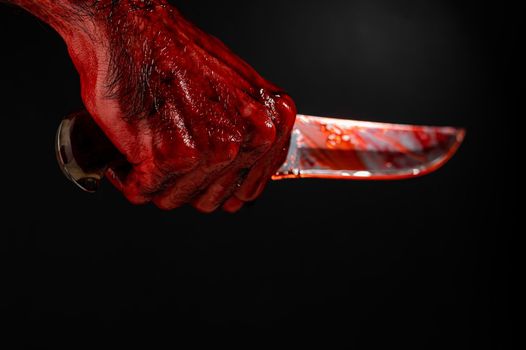 A man with bloody hands brandishes a knife on a black background