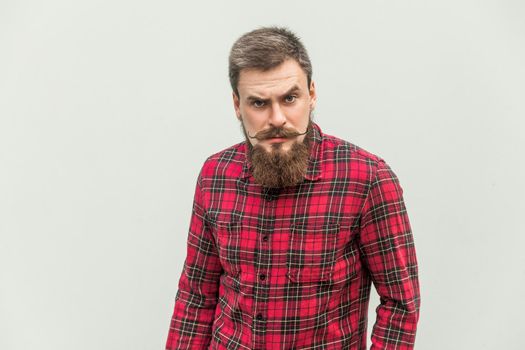 Angry, aggressive. Handsome businessman with beard and handlebar mustache looking at camera with angry face . studio shot, on gray background.