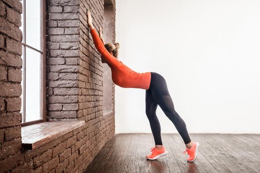 Activity woman doing cat pose near bric wall. Studio shot