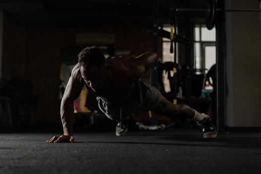 African american man doing one arm push ups in the gym