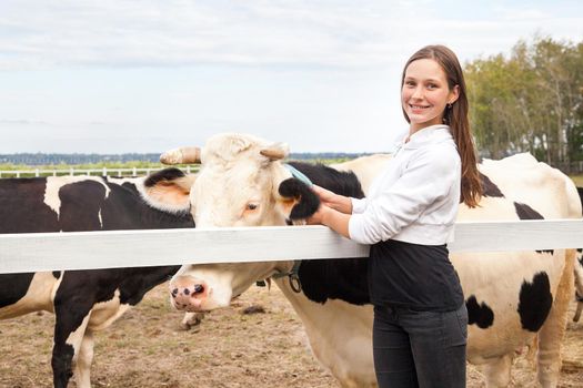Play with animals, friendship with cow. Smiling farmer woman standing by cattle outside. Outdoor, autumn
