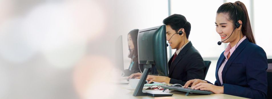 Business people wearing headset working in office in widen view to support remote customer or colleague. Call center, telemarketing, customer support agent provide service on telephone video call.