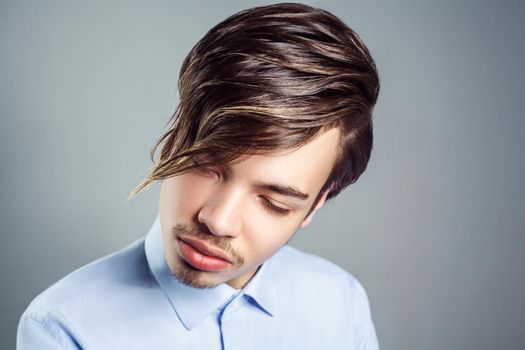 Portrait of young man with long fringe hairstyle on his eyes. studio shot. clossed eyes.