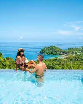 a young couple of men and women at a swimming pool during a vacation on a tropical island. man and woman in infinity pool during sunset. luxury vacation in Thailand pool of a luxury pool villa