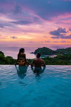 a young couple of men and women at a swimming pool during a vacation on a tropical island. man and woman in infinity pool during sunset. luxury vacation in Thailand pool of a luxury pool villa