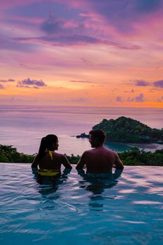 a young couple of men and women at a swimming pool during a vacation on a tropical island. man and woman in infinity pool during sunset. luxury vacation in Thailand pool of a luxury pool villa