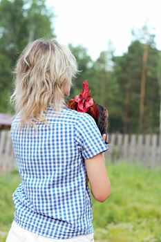 Beautiful woman in the chicken farm holding a chicken, healthy lifestyle and organic farming concept. Rooster and cat