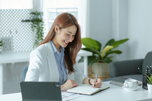 Portrait of a young businesswoman or business owner working with a notebook and tablet computer at office room.