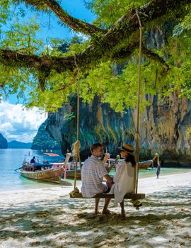 Koh Lao Lading near Koh Hong Krabi Thailand, beautiful beach with longtail boats, a couple of European men, and an Asian woman on the beach.