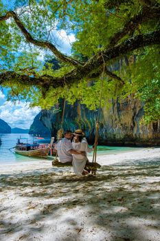 Koh Lao Lading near Koh Hong Krabi Thailand, beautiful beach with longtail boats, a couple of European men, and an Asian woman on the beach.