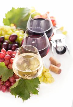 glasses of red and white wine and ripe grapes on table