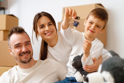 Portrait of happy family with cardboard boxes in new house at moving day, close up