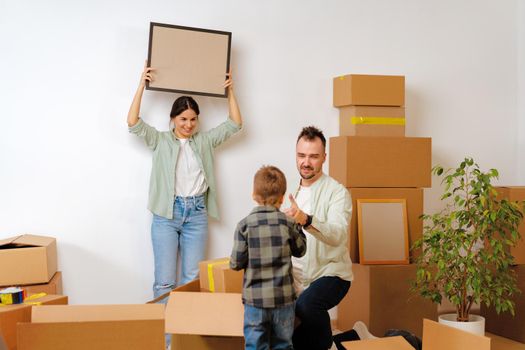 Young parents and son having fun during moving day to new house, portrait