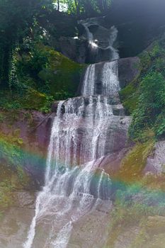 A mountain waterfall flows over the rocks. Waterfall cascade on mossy rocks. Waterfall cascade