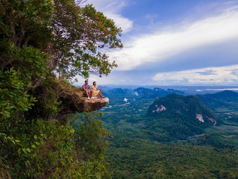 Dragon Crest mountain Krabi Thailand, a Young traveler sits on a rock that overhangs the abyss, with a beautiful landscape. Dragon Crest or Khuan Sai at Khao Ngon Nak Nature Trail in Krabi, Thailand