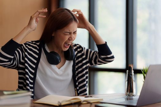 Image of Asian Business woman stressed and screaming after end of video conference at home. Expression and Emotional concept