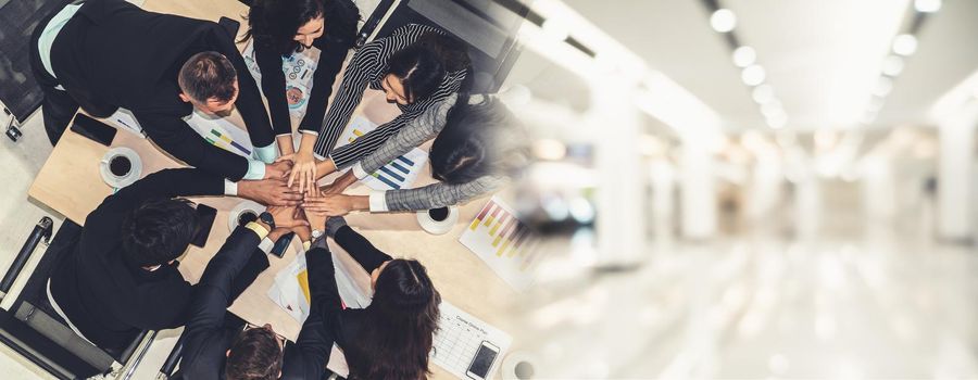 Happy business people celebrate teamwork success together with joy at office table shot from top view . Young businessman and businesswoman workers express cheerful victory in broaden view .