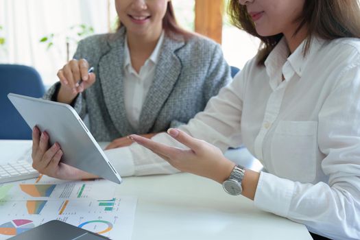 young Asian businesswoman using tablet computers to plan marketing strategies and invest to profit from customers.