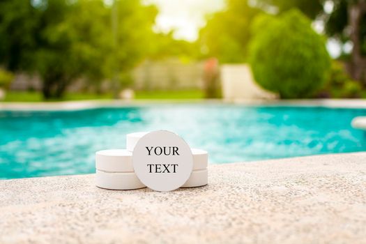 Chlorine tablets for swimming pool disinfection with space for text. Chlorine tablets for swimming pool cleaning with space for text, chlorine tablets on the edge of a swimming pool