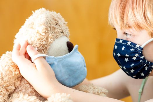 Young girl training to use a face mask during the pandemic -Focus on the teddy.