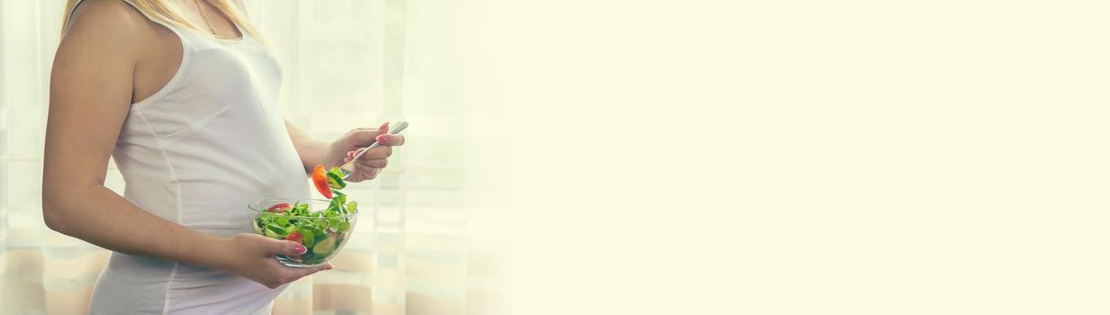 A pregnant woman eats a salad with vegetables. Selective focus. Food.