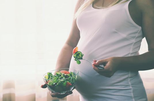 A pregnant woman eats a salad with vegetables. Selective focus. Food.