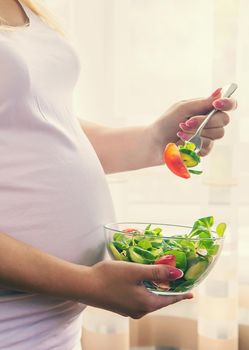A pregnant woman eats a salad with vegetables. Selective focus. Food.
