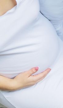 A pregnant woman hugs her belly. Selective focus.