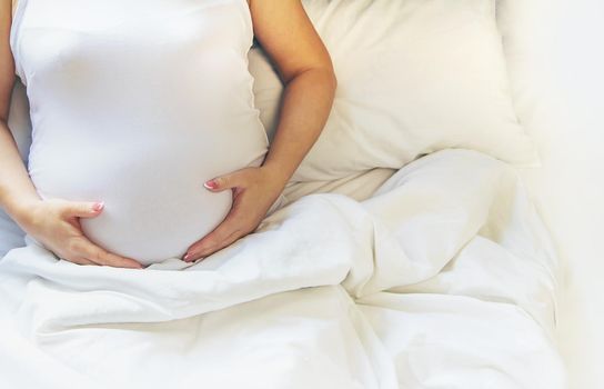 A pregnant woman hugs her belly. Selective focus. People.