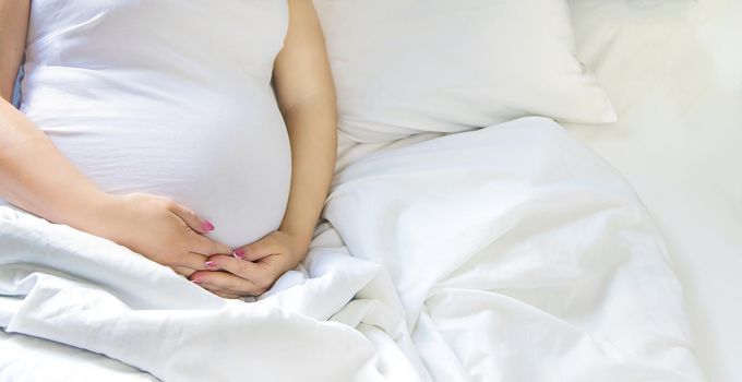 A pregnant woman hugs her belly. Selective focus. People.