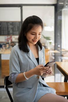 Pretty asian woman sitting in coffee shop and using smart phone.