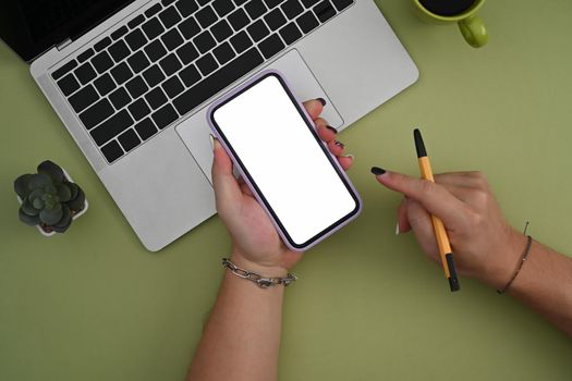 Above view young woman holding pen and pointing on screen of smart phone.