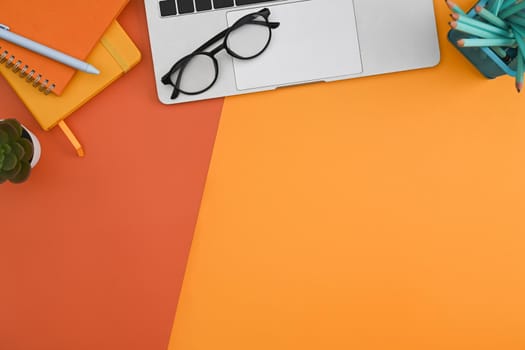 Flat lay, laptop computer, glasses, notebook and stationery on colorful background.