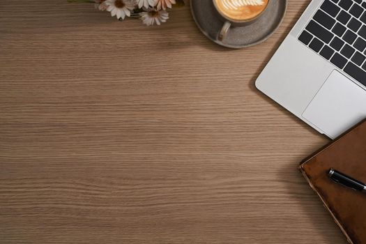 Simple workplace with computer laptop, coffee cup, notebook and flower pot.