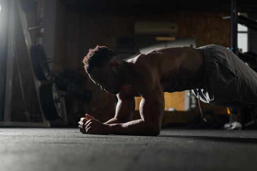 Shirtless african american man doing an elbow plank in the gym