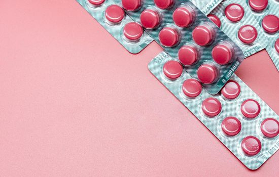 Top view of pink tablets pill and blister pack of pills on pink background. Prescription drugs. Pharmaceutical industry. Health care and medicine. Tablets pills production. Vitamins and supplements.