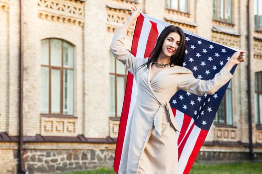Beautiful happy woman with American flag celebrating independence day.