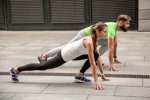 Young sport couple in starting position prepared to compete and run. using sport tracker.