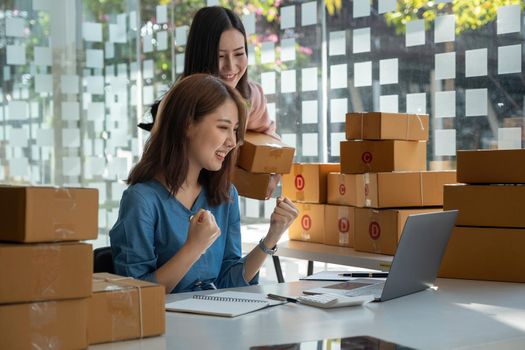 startup small business owner working at workplace. Success happy two asian wooman freelance seller check product order for delivery. Online selling, e-commerce, shipping concept.
