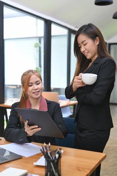 Two young employees sharing idea, discussing business information together at co working space.