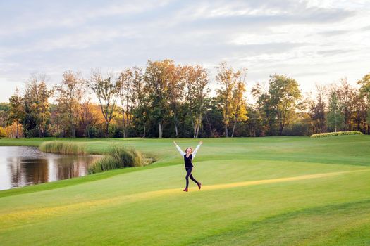 Girl runs on the green grass of the golf course. The girl happiness. Outdoor shot